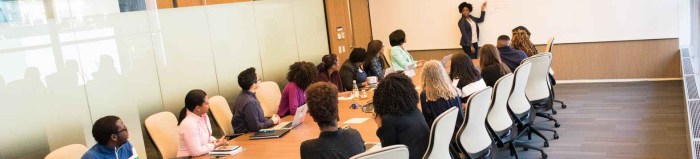 people sitting on beige rolling chairs on brown wooden table inside room