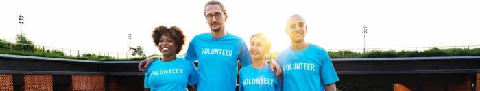 four people wearing blue crew neck shirts standing on lawn