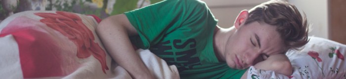man wearing green printed crew neck shirt while sleeping