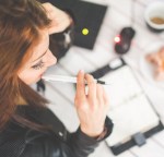 young woman thinking with pen while working studying at her desk